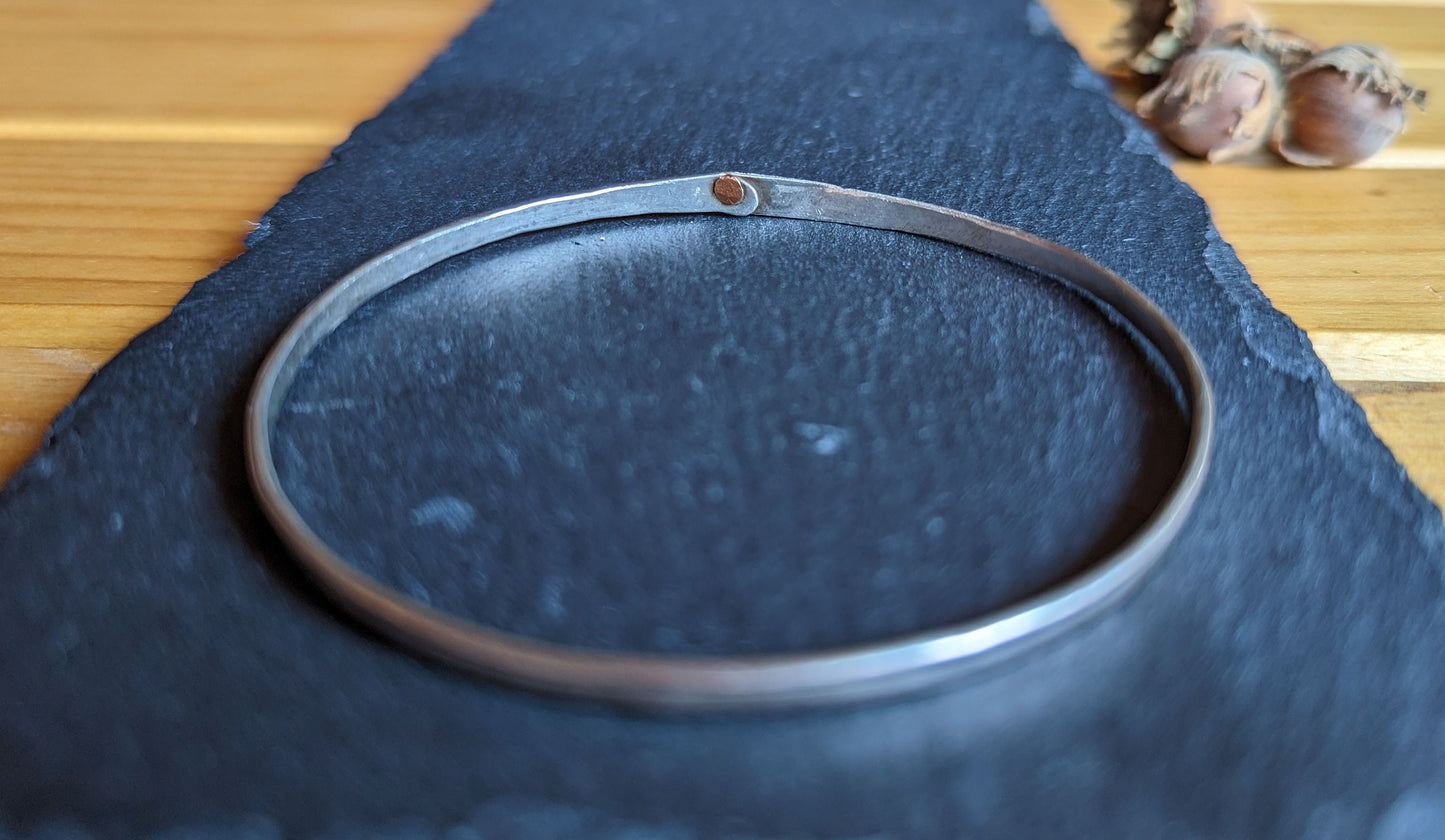 Hammered silver bangle with copper rivet