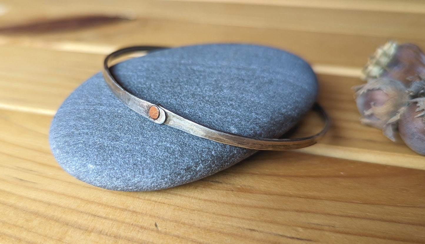 Hammered silver bangle with copper rivet