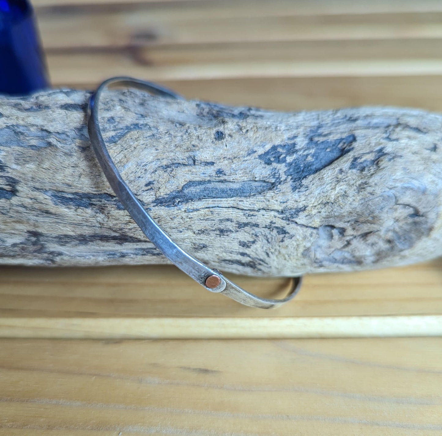 Hammered silver bangle with copper rivet