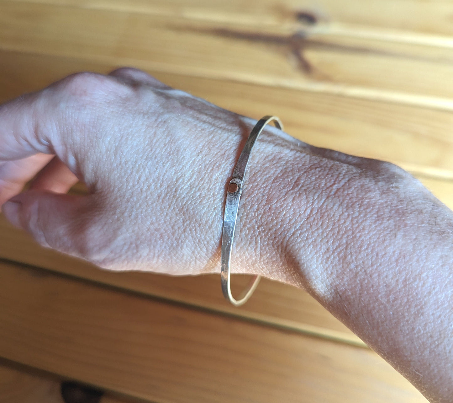 Hammered silver bangle with copper rivet