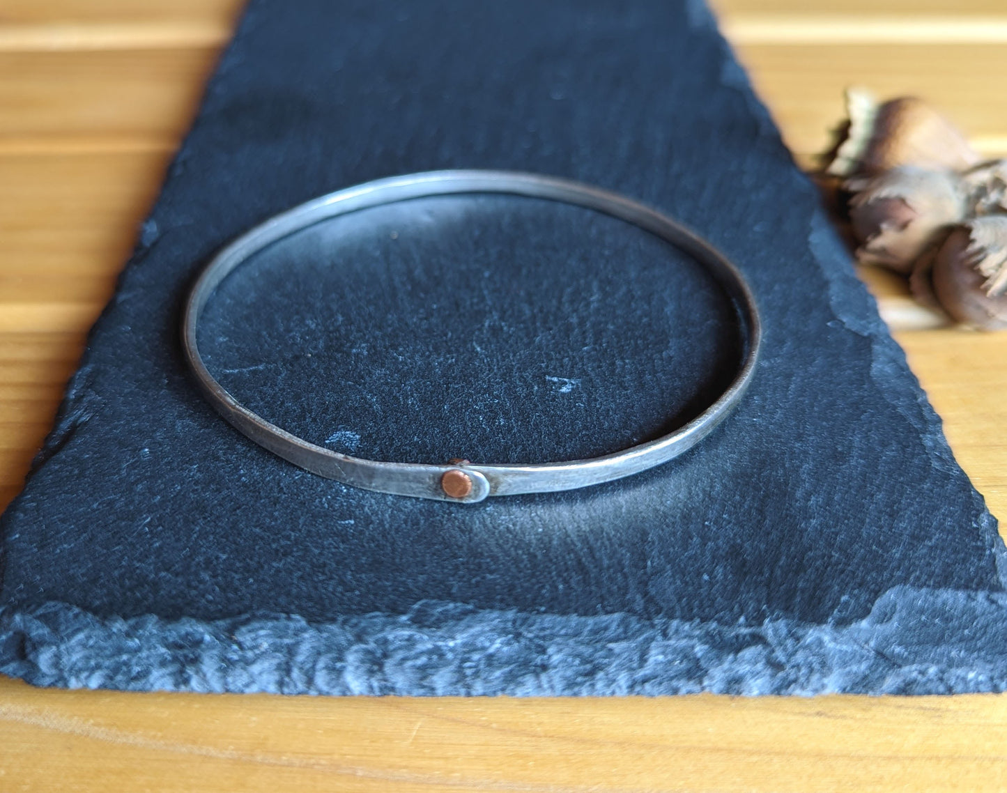 Hammered silver bangle with copper rivet